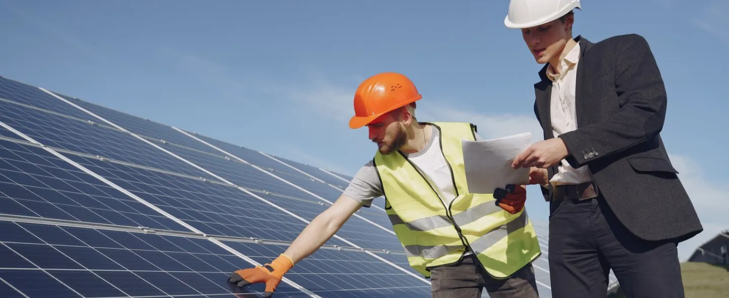 An installer and an engineer inspecting a large solar array under a clear sky