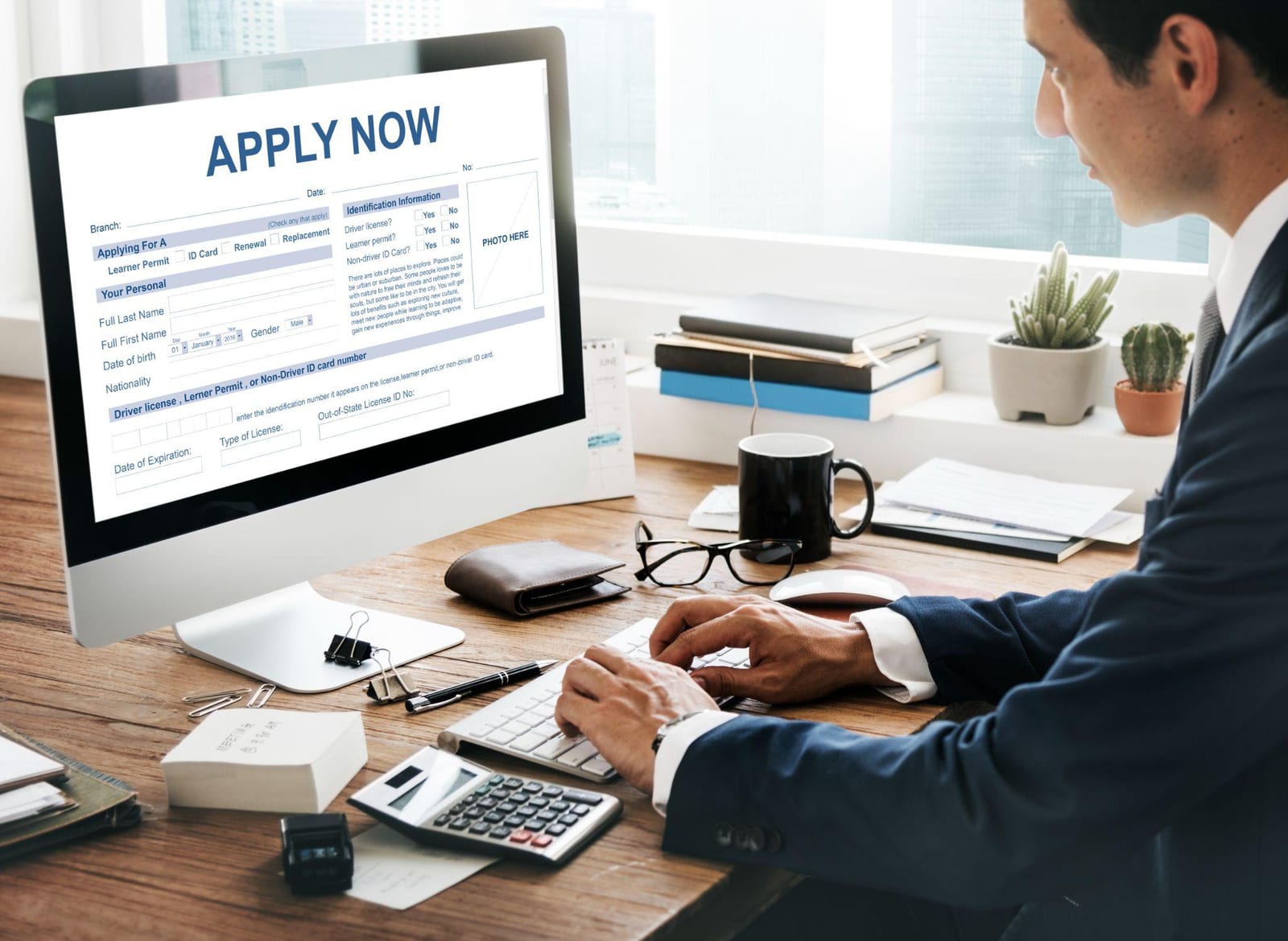 A person at a desk filling in an online application form on a computer screen