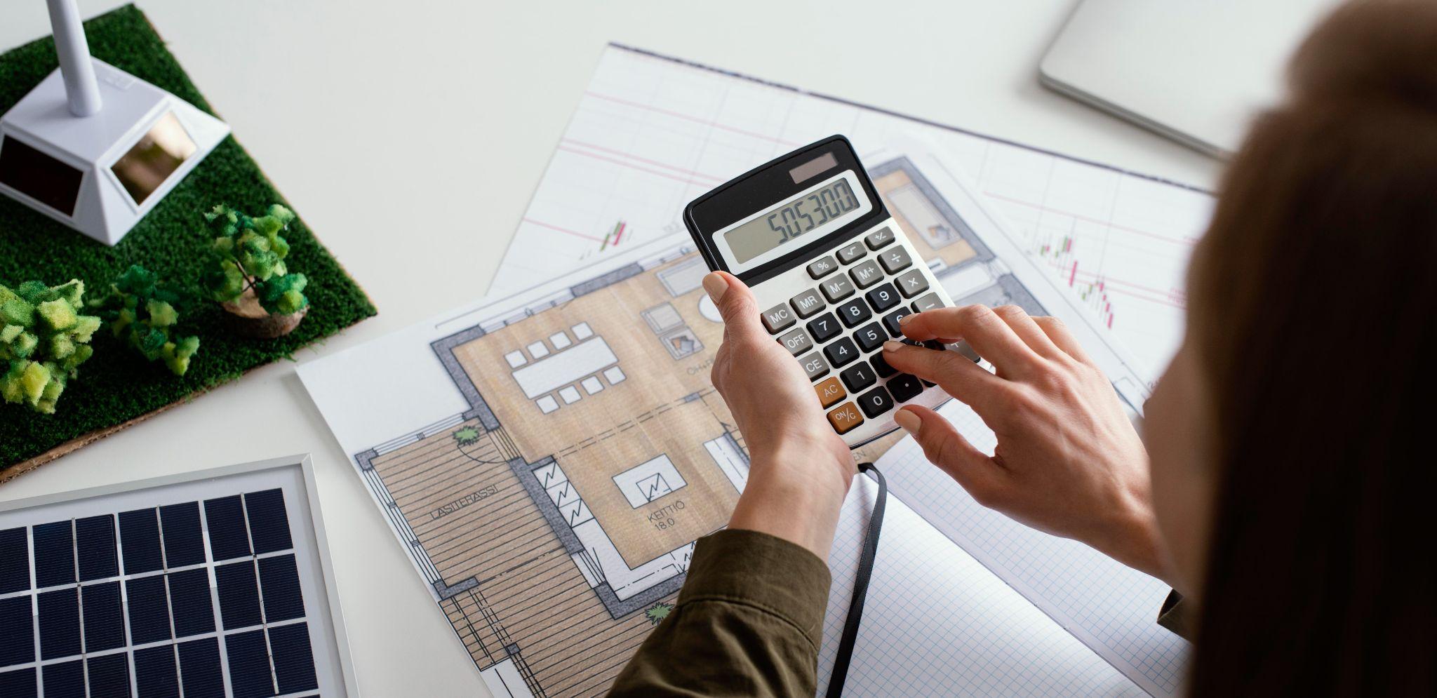 Working out solar payback on house plans with a calculator next to a model solar panel