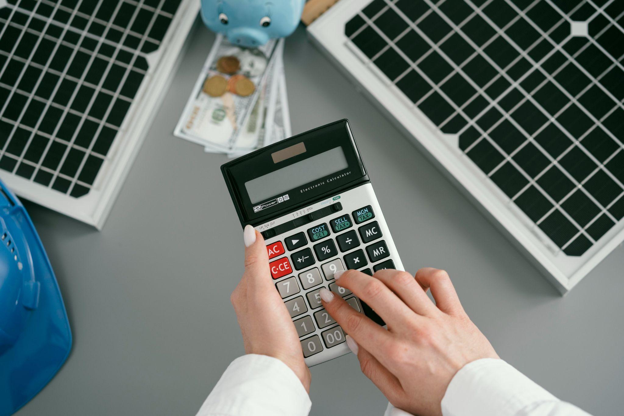 Working out battery savings on a calculator beside solar panels and a piggy bank